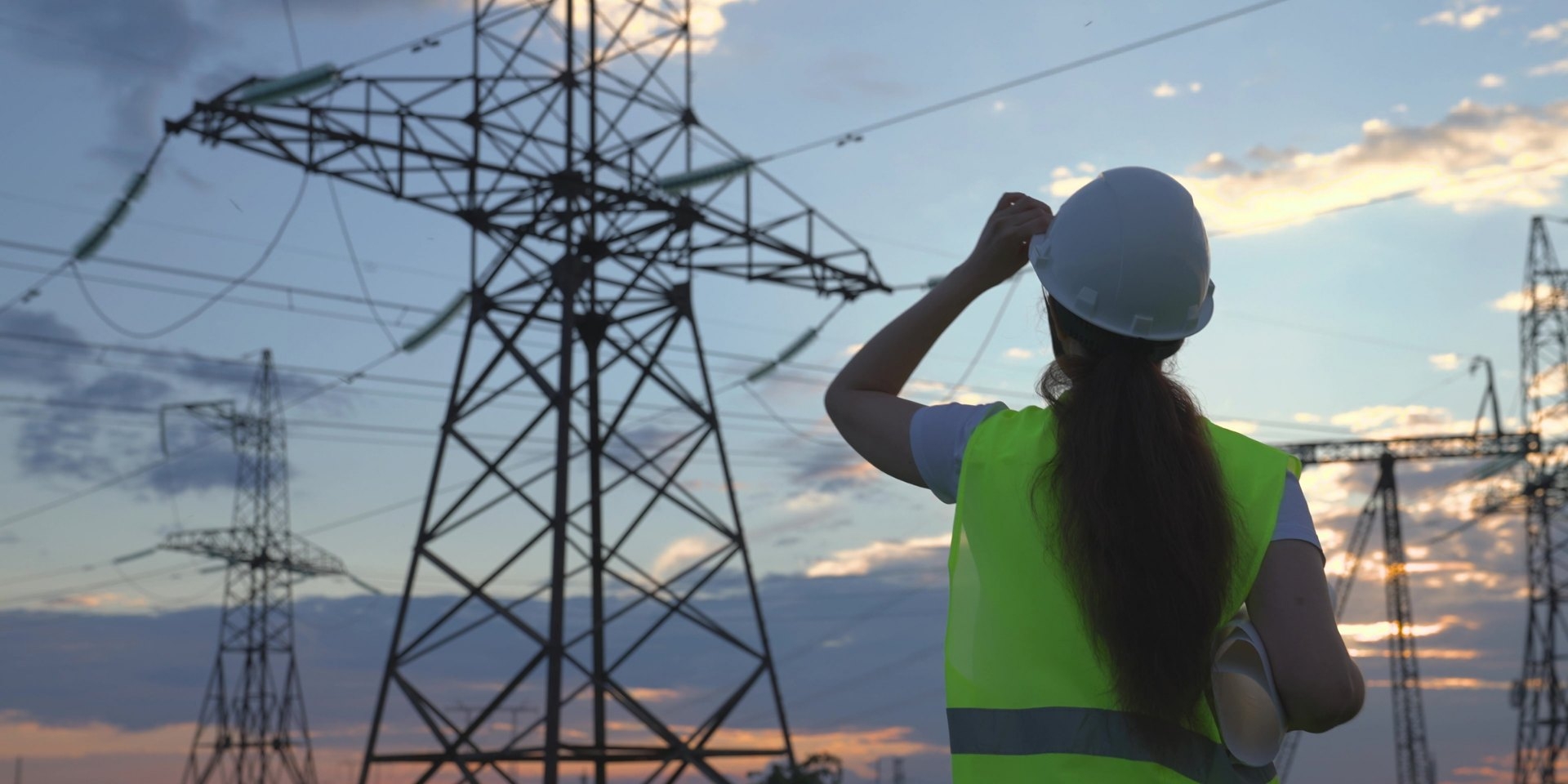 Engineer in hi-vis looking up at a transmission tower