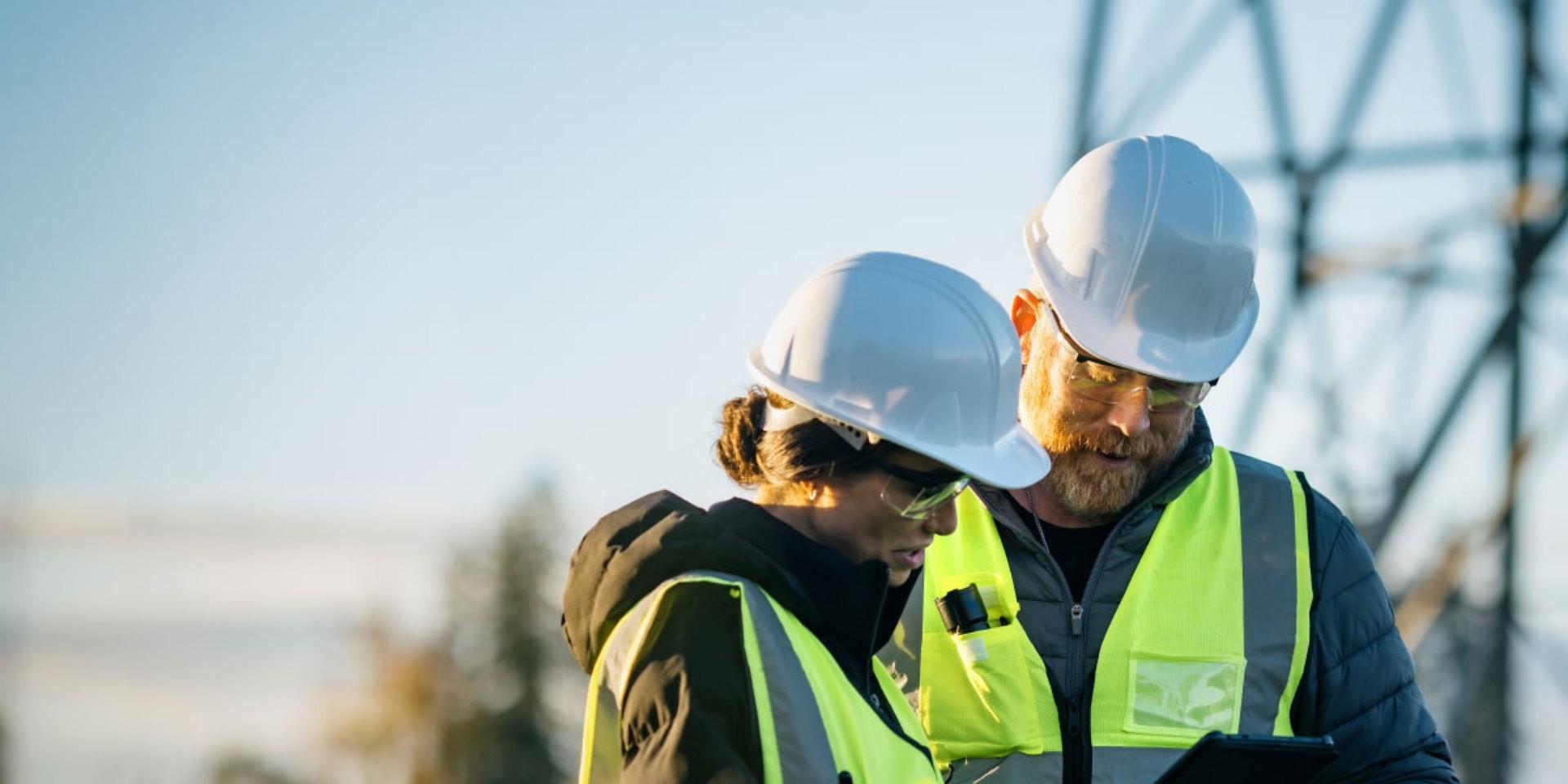 Two engineers in hard hats and hi-vis reviewing work on site